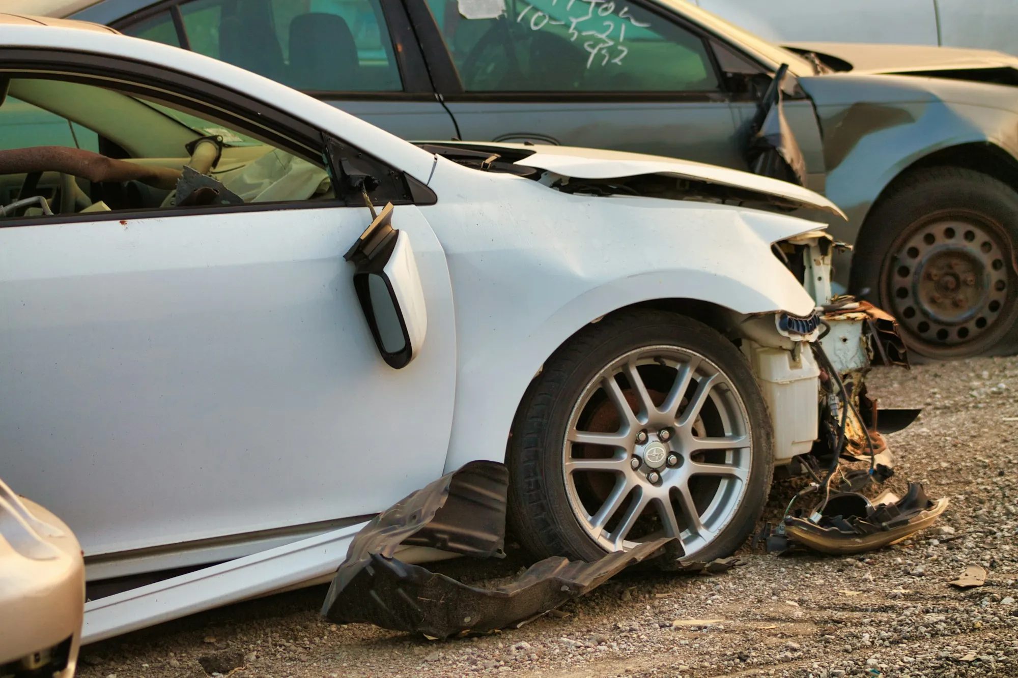 Silver car with a crushed front end and torn bumper after a collision