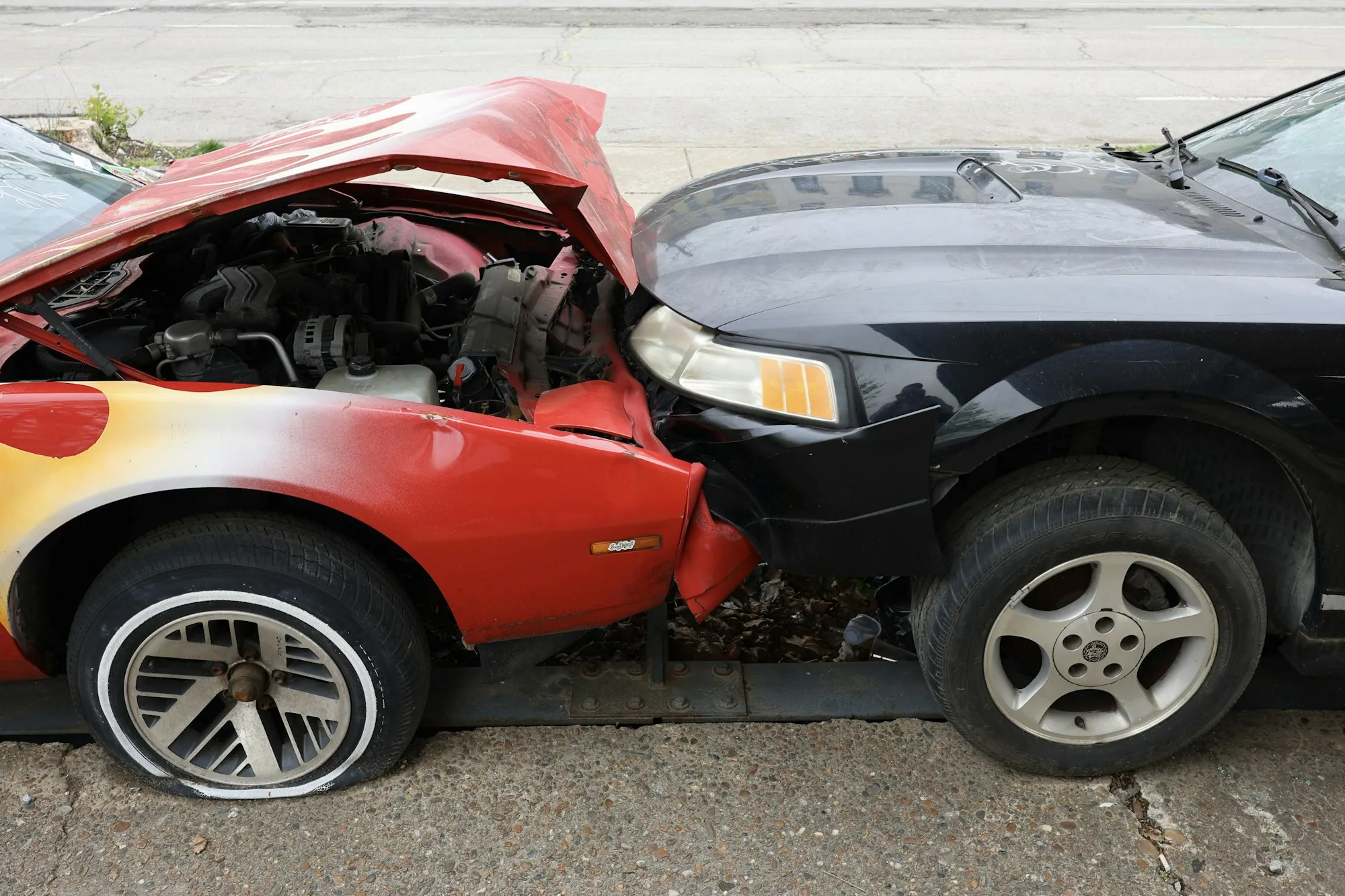 Red car and black car crumpled together after a collision