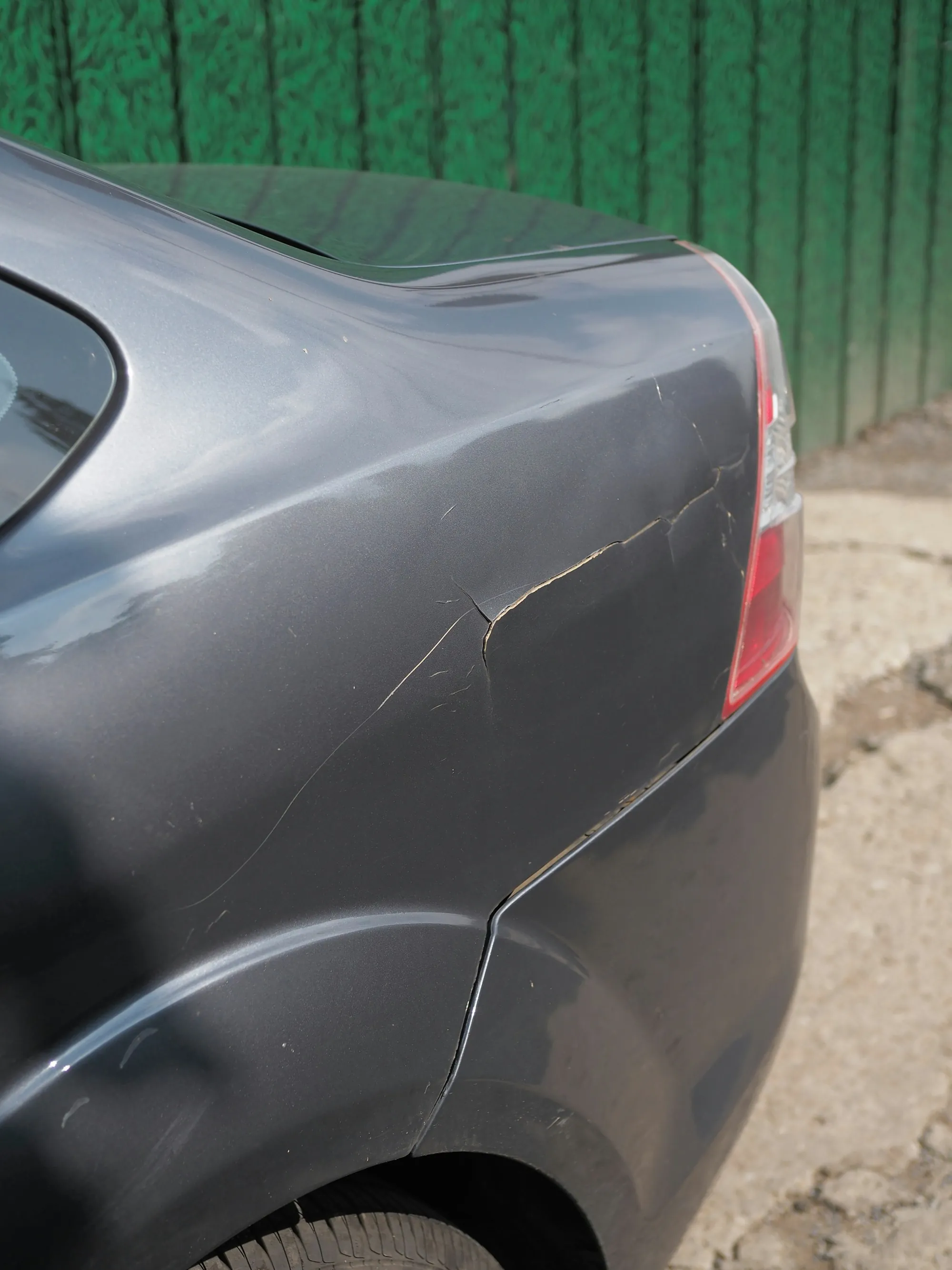 Gray car's rear fender with scrapes along the paint