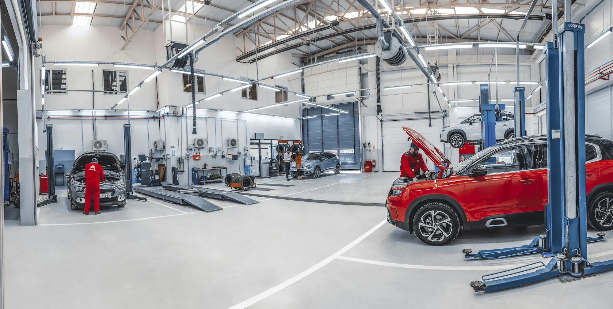 Wide view of a clean repair shop with cars raised on blue lifts